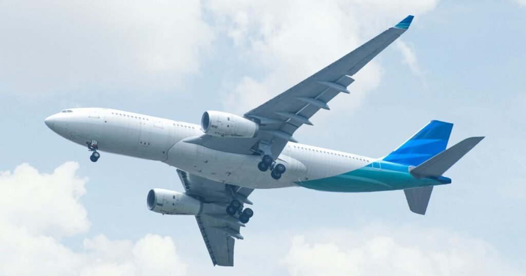 A large passenger airplane in flight against a cloudy sky. This image represents the "Fly" portion of a "Fly + Drive" trip from Phoenix to Sequoia National Park.